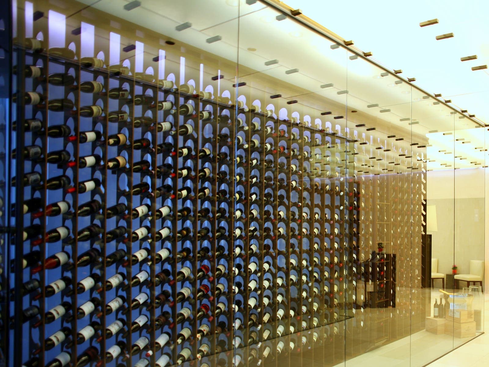 A brick-vaulted wine cellar with extensive bottle racks and warm chandelier lighting.